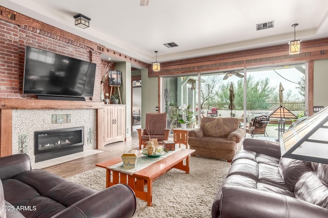 living area with visible vents, a tile fireplace, and wood finished floors