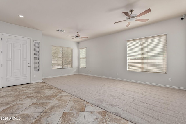 unfurnished room featuring a wealth of natural light, light colored carpet, visible vents, and baseboards