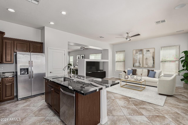 kitchen with open floor plan, stainless steel appliances, dark countertops, and a sink