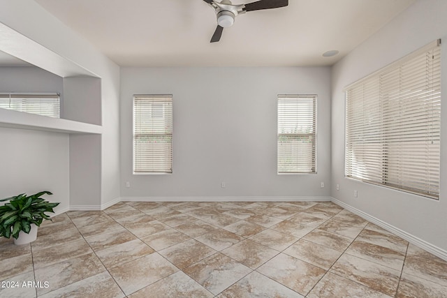 unfurnished room featuring ceiling fan, light tile patterned floors, and baseboards