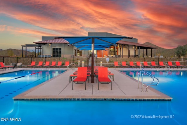 pool at dusk featuring a patio area