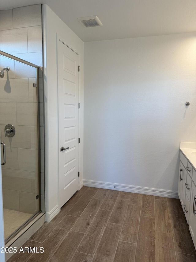 bathroom featuring a shower with shower door and vanity