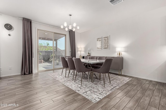 dining space with baseboards, wood finish floors, a notable chandelier, and visible vents