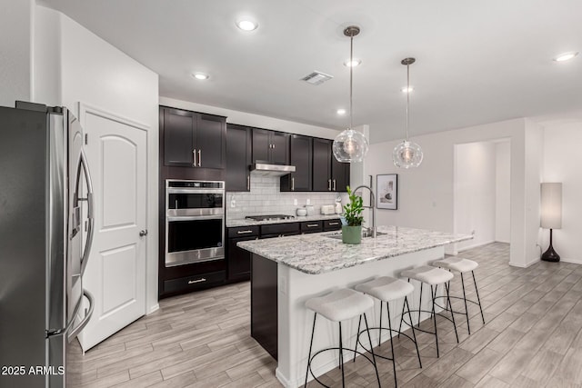 kitchen with visible vents, a sink, appliances with stainless steel finishes, wood tiled floor, and backsplash