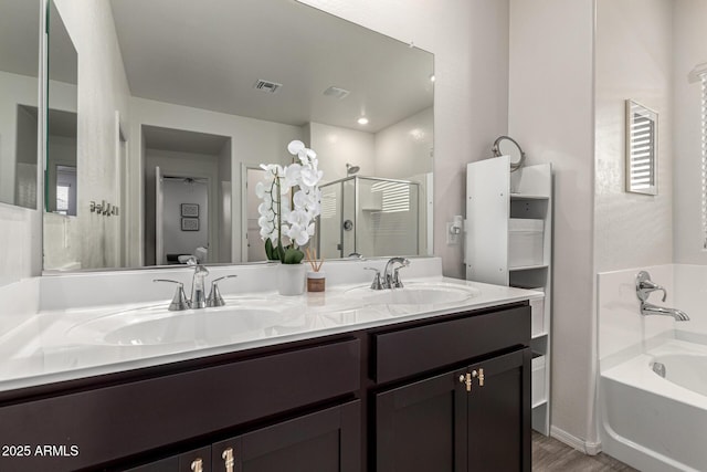 bathroom featuring a stall shower, double vanity, a sink, and visible vents