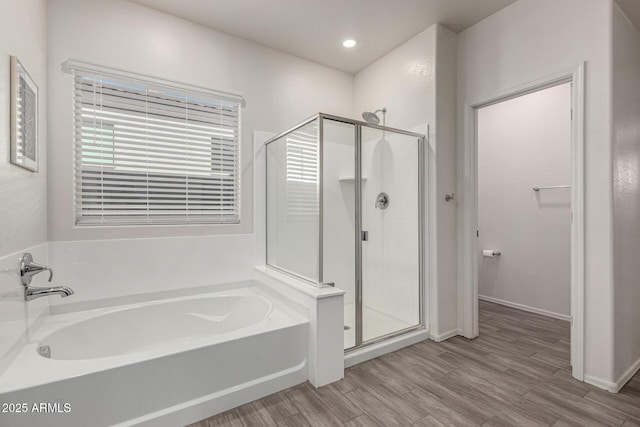 bathroom with a shower stall, recessed lighting, a bath, and wood finished floors