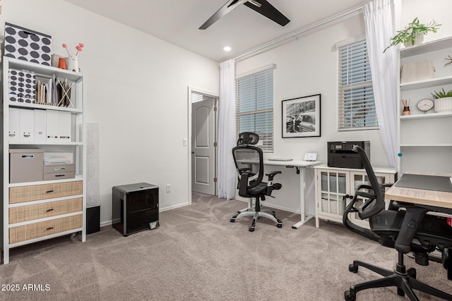 carpeted office space with baseboards and a ceiling fan