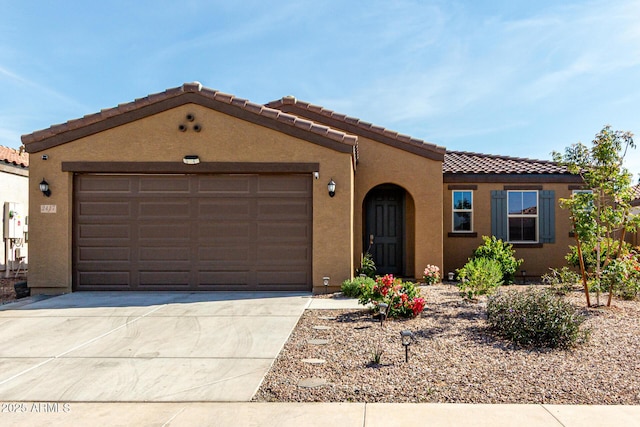 mediterranean / spanish house with concrete driveway, stucco siding, a tiled roof, and a garage