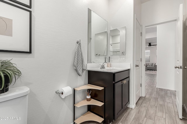bathroom with toilet, vanity, a ceiling fan, and wood tiled floor