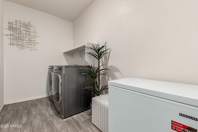 laundry room with washing machine and dryer, laundry area, baseboards, and wood finished floors