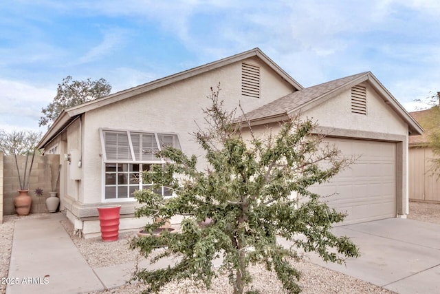 view of front of house with driveway, an attached garage, fence, and stucco siding