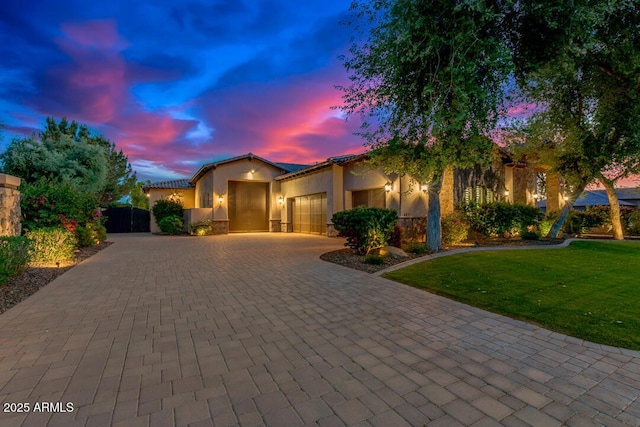 view of front facade featuring a tile roof, a lawn, stucco siding, decorative driveway, and an attached garage