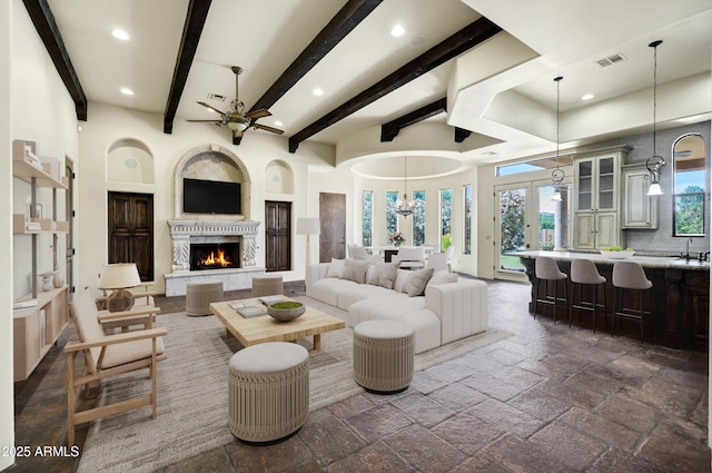 2300 E Sanoque Ct, Gilbert, AZ 85298 - living area with ceiling fan, recessed lighting, stone tile flooring, a warm lit fireplace, and beamed ceiling