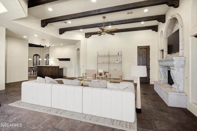 2300 E Sanoque Ct, Gilbert, AZ 85298 - living area featuring arched walkways, recessed lighting, stone tile floors, a high end fireplace, and beamed ceiling