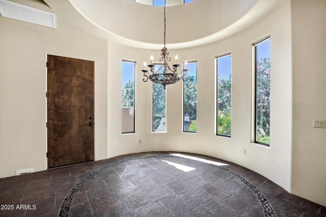 2300 E Sanoque Ct, Gilbert, AZ 85298 - unfurnished dining area featuring inlaid floor details, stone tile flooring, a chandelier, and plenty of natural light