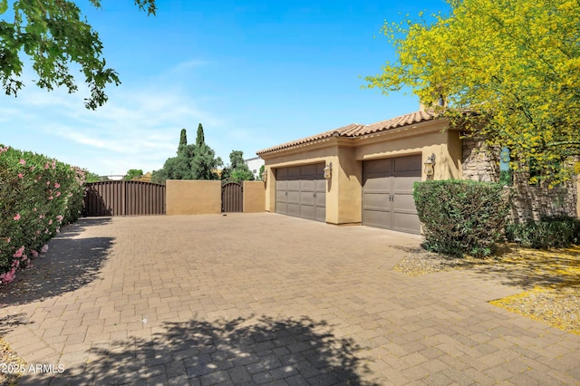 2300 E Sanoque Ct, Gilbert, AZ 85298 - view of side of home featuring a gate, stucco siding, decorative driveway, an attached garage, and a tiled roof