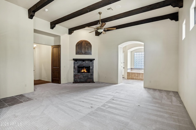 2300 E Sanoque Ct, Gilbert, AZ 85298 - unfurnished living room featuring ceiling fan, carpet, arched walkways, a stone fireplace, and beam ceiling