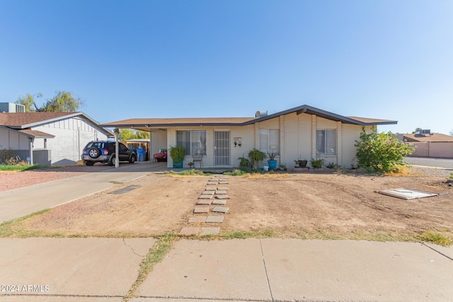 ranch-style home with concrete driveway, an attached carport, and central air condition unit