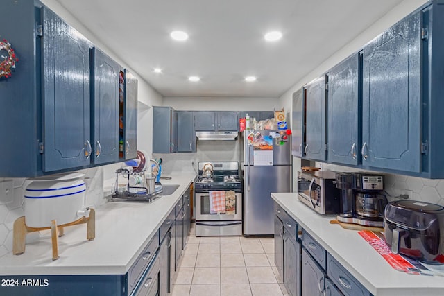 kitchen with under cabinet range hood, stainless steel appliances, light countertops, and light tile patterned flooring