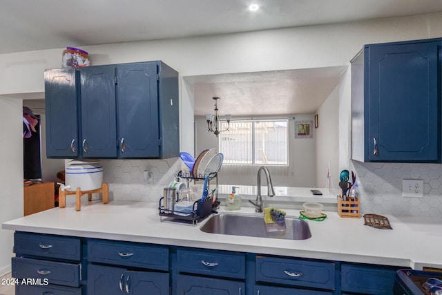 kitchen with light countertops, blue cabinetry, backsplash, and a sink