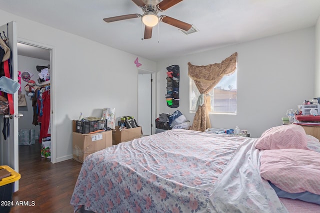 bedroom featuring a walk in closet, a closet, visible vents, a ceiling fan, and wood finished floors