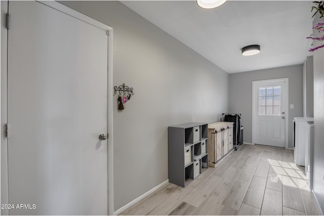 foyer entrance with light hardwood / wood-style floors and independent washer and dryer