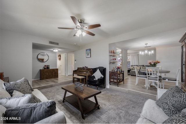 living room with ceiling fan with notable chandelier