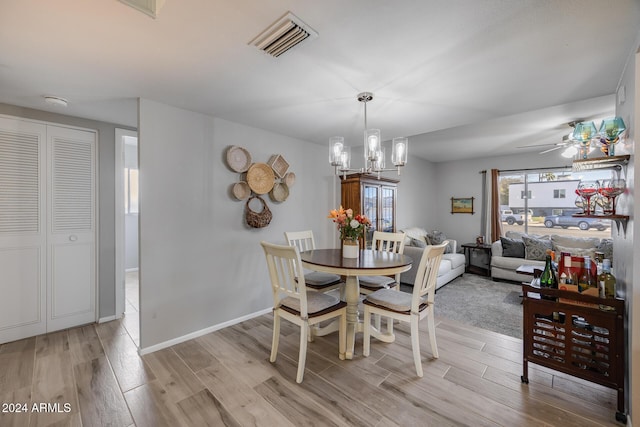 dining area featuring ceiling fan with notable chandelier and light hardwood / wood-style floors