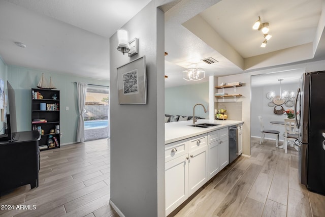 kitchen with white cabinetry, sink, hanging light fixtures, an inviting chandelier, and appliances with stainless steel finishes