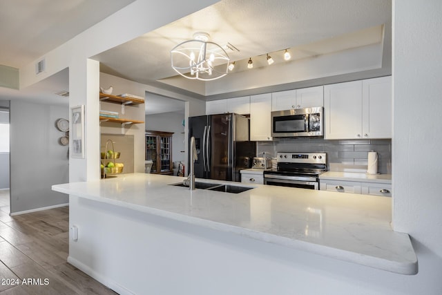 kitchen featuring white cabinets, hanging light fixtures, light stone counters, kitchen peninsula, and stainless steel appliances