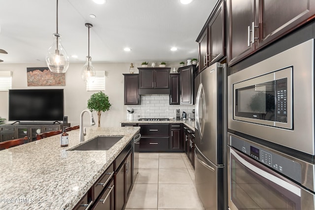 kitchen with light stone counters, sink, dark brown cabinetry, and stainless steel appliances