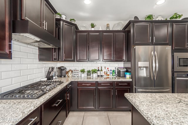 kitchen featuring stainless steel appliances, light tile patterned floors, custom exhaust hood, backsplash, and light stone countertops