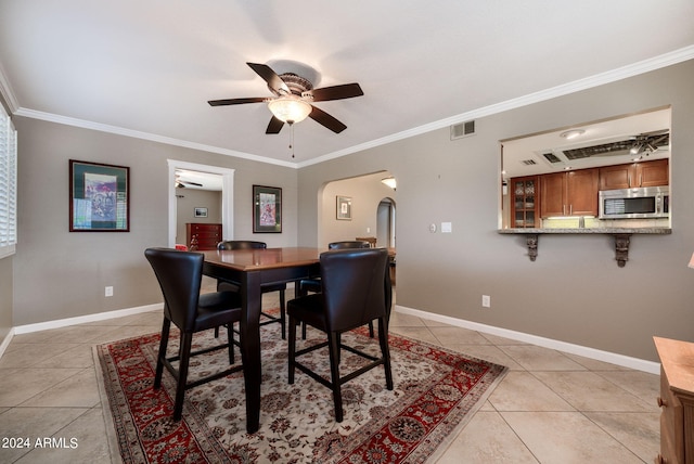 dining room with ceiling fan, crown molding, and light tile patterned flooring