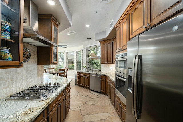 kitchen with light stone counters, visible vents, appliances with stainless steel finishes, glass insert cabinets, and wall chimney range hood