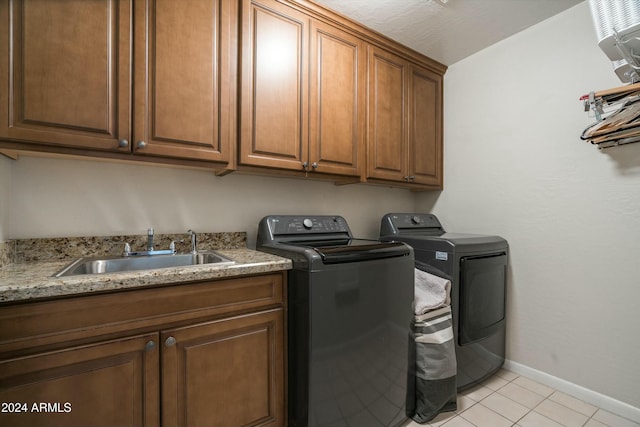 laundry area with light tile patterned floors, a sink, baseboards, washer and dryer, and cabinet space