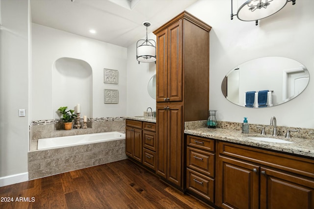 bathroom featuring two vanities, a sink, a bath, and wood finished floors