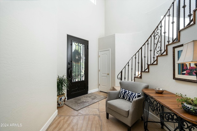 entrance foyer featuring a towering ceiling, baseboards, and stairs