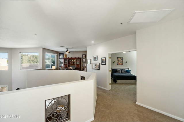 hall featuring baseboards, visible vents, light carpet, and an upstairs landing