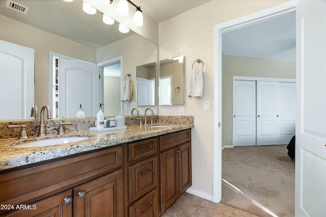 bathroom with double vanity, baseboards, visible vents, and a sink