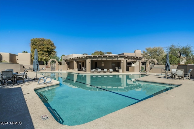 community pool with a patio area, fence, and a pergola