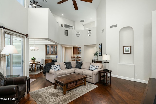 living room with dark wood-style floors, arched walkways, visible vents, ceiling fan, and baseboards