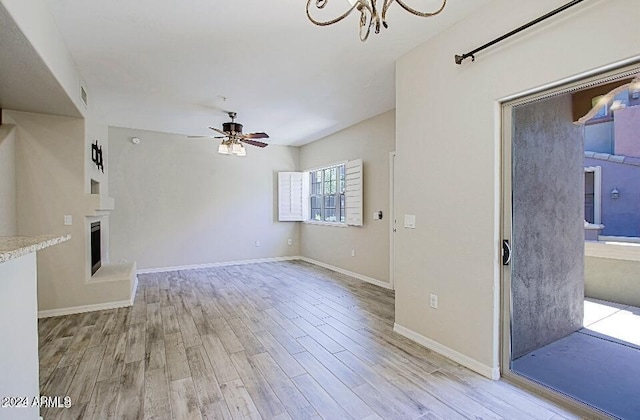 3935 E Rough Rider Rd Unit 1101, Phoenix, AZ 85050 - unfurnished living room featuring light wood-type flooring, a ceiling fan, a fireplace with raised hearth, and a chandelier