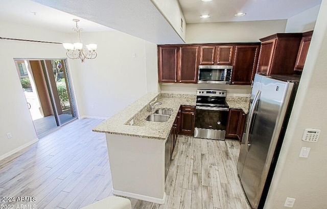 3935 E Rough Rider Rd Unit 1101, Phoenix, AZ 85050 - kitchen with appliances with stainless steel finishes, a peninsula, light wood finished floors, a chandelier, and light stone counters