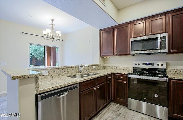 3935 E Rough Rider Rd Unit 1101, Phoenix, AZ 85050 - kitchen featuring stainless steel appliances, light wood-style floors, a peninsula, a chandelier, and light stone countertops