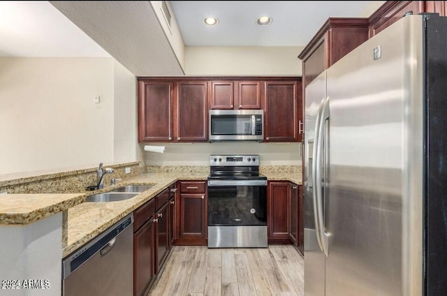 3935 E Rough Rider Rd Unit 1101, Phoenix, AZ 85050 - kitchen featuring stainless steel appliances, dark brown cabinets, light stone countertops, a peninsula, and light wood finished floors