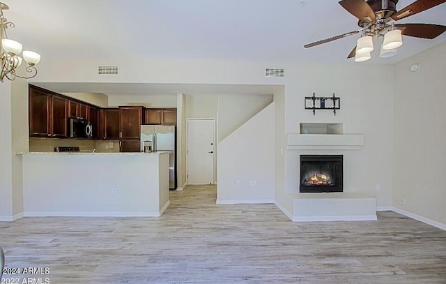 3935 E Rough Rider Rd Unit 1101, Phoenix, AZ 85050 - kitchen featuring light wood-type flooring, appliances with stainless steel finishes, open floor plan, and a lit fireplace