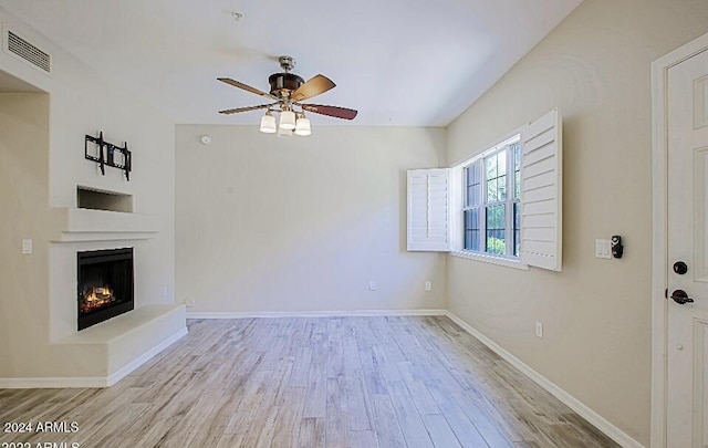 3935 E Rough Rider Rd Unit 1101, Phoenix, AZ 85050 - unfurnished living room with ceiling fan, wood finished floors, and a warm lit fireplace