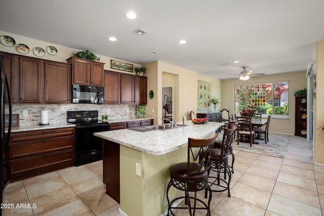 kitchen featuring visible vents, tasteful backsplash, a sink, black appliances, and light tile patterned flooring