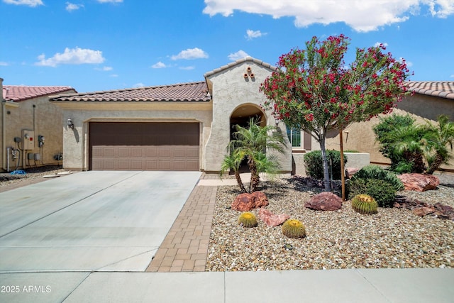 mediterranean / spanish home with concrete driveway, a garage, a tile roof, and stucco siding
