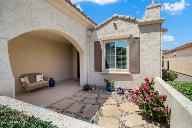 view of exterior entry with a chimney and stucco siding